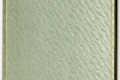 A closed, textured book with a light green cover and gold lining