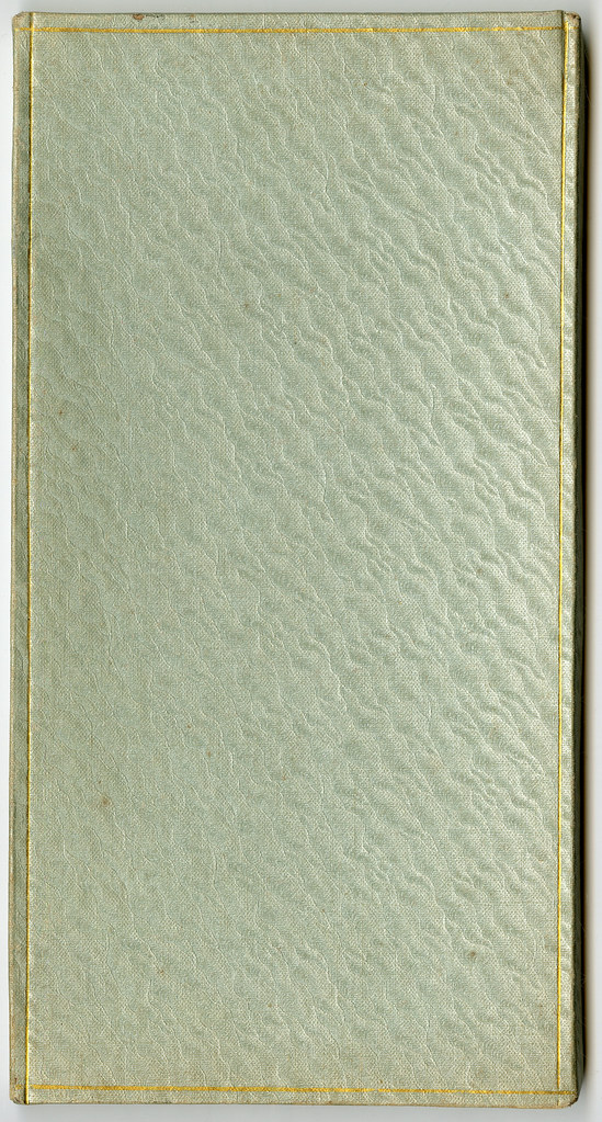 A closed, textured book with a light green cover and gold lining